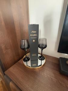 two wine glasses and a box on a table at Stylish King Downtown in Podgorica