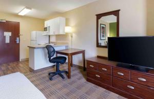a hotel room with a desk and a tv and a chair at Extended Stay America Select Suites - Des Moines - Urbandale in Clive