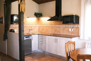 a kitchen with white cabinets and a sink and a table at Casa Rural Graner in Sant Llorenc de Morunys