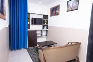 a room with a chair and a table and blue curtains at Wisdom Villa in Kumasi