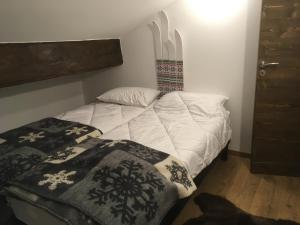 Un dormitorio con una cama blanca con una manta. en Chalet 1829 en Sainte-Foy-Tarentaise