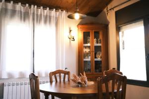 a dining room with a table and chairs and windows at Casa Rural Graner in Sant Llorenç de Morunys