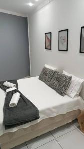 een witte slaapkamer met een bed met witte lakens en kussens bij Apartamento a 1200m da praia 2 quartos in Vila Velha