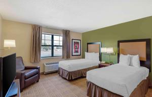 a hotel room with two beds and a flat screen tv at Extended Stay America Select Suites - Chicago - Rolling Meadows in Rolling Meadows