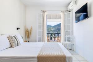 a white bedroom with a bed and a balcony at Aperitton Hotel in Skopelos Town