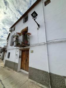 - un bâtiment blanc avec une porte et un balcon dans l'établissement Alojamiento Manzanilla, à Iznatoraf