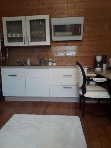 een keuken met witte kasten en een tafel en stoelen bij Ferienwohnung besonderer Art in Windeck