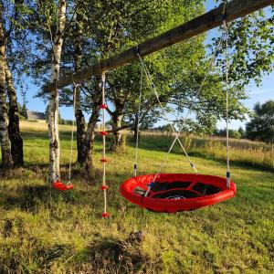 an empty red swing in a field with trees at Apartmány RADOST in Kovářská