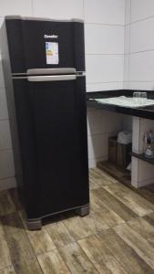 a black refrigerator in a kitchen next to a counter at Pousada toca da coruja in Contagem