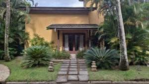 a house with a pathway leading to the front door at Condominio Vila dos Tucanos Canto Moreira 1 quadra da praia ,q tenis, piscina ,portaria 24 hs in Maresias