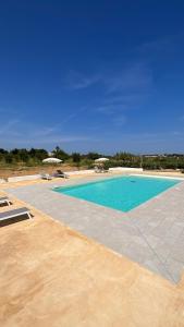 einen Pool mit blauem Wasser und Sonnenschirmen in der Unterkunft Blu Home Scopello in Castellammare del Golfo