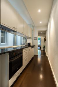 a kitchen with white cabinets and a black oven at Old town apt in the heart of Thun with garden in Thun