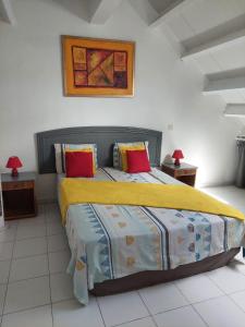 1 dormitorio con 1 cama grande con almohadas amarillas y rojas en Pelican en Saint Martin