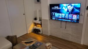 ein Wohnzimmer mit einem Flachbild-TV an einer Backsteinwand in der Unterkunft Apartamento EL REAL - Espartinas - SEVILLA in Espartinas