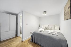 ein weißes Schlafzimmer mit einem Bett und einem Spiegel in der Unterkunft CosyLiving Apartments London Paddington in London
