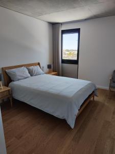 ein Schlafzimmer mit einem großen weißen Bett und einem Fenster in der Unterkunft Apartamento T3 junto à ria e ao mar! in Gafanha da Nazaré