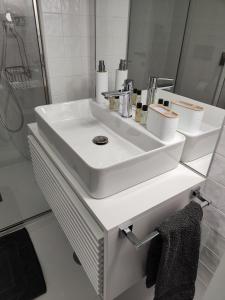 ein weißes Bad mit einem Waschbecken und einer Dusche in der Unterkunft Apartamento T3 junto à ria e ao mar! in Gafanha da Nazaré