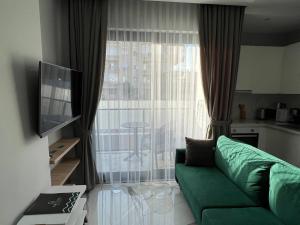 uma sala de estar com um sofá verde em frente a uma janela em The Yacht apartments em Alanya