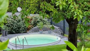 a hot tub in a garden with a tree at Superior - Ferienhaus am Engelsbach mit Pool im Thüringer Wald in Engelsbach
