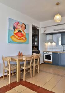 une cuisine avec une table, des chaises et un tableau dans l'établissement Aqua Bliss, à Xerokampos