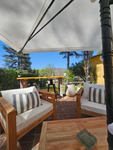 un patio con 2 sofás blancos bajo una sombrilla en Posada Aitue en Villa General Belgrano