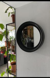 un espejo redondo en una pared con plantas en Grand f2 au calme centre de village, en Dampierre-les-Bois