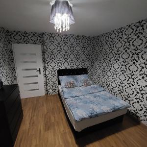 a small bedroom with a bed and a chandelier at Apartament Chopina 17 in Włocławek