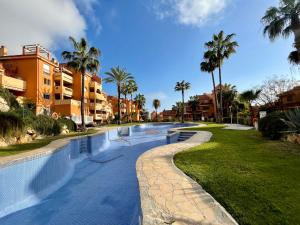 una piscina en un complejo con palmeras en Apartamento con vistas al mar en Reserva de Marbella, en Marbella