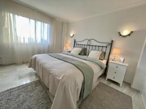 Un dormitorio blanco con una cama grande y una ventana en Apartamento con vistas al mar en Reserva de Marbella, en Marbella