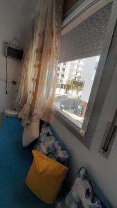 a room with a window with pillows and a couch at appartement central plein d’expérience in Martil