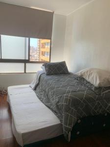a bed sitting in a room with a window at Campanario 104 con factura in Iquique