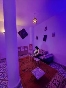 a person sitting on a couch in a purple room at Mask Off Artel in Essaouira