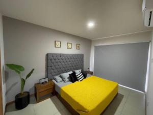 a bedroom with a yellow bed and a plant at Brittania 601, cómodo, excelente ubicación in Guadalajara