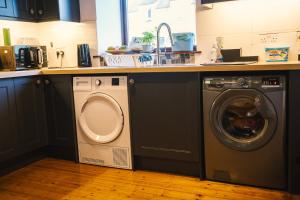 uma cozinha com uma máquina de lavar roupa e um lavatório em 3-bedroom house for outdoor holidays em Alyth