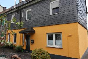 une maison jaune avec un toit noir dans l'établissement Privatzimmer Haus Grünewald, à Solingen