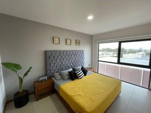 a bedroom with a yellow bed and a large window at Brittania 601, cómodo, excelente ubicación in Guadalajara