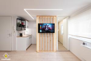 roomaki - new & stylish studio in the center with parking في خالكيذا: غرفة معيشة فيها تلفزيون على جدار