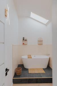 IoanaGuestHouse في توردا: حوض استحمام أبيض يجلس على أرضية من البلاط في الحمام