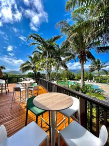d'un balcon avec des tables, des chaises et des palmiers. dans l'établissement Rivland Resort, à Païta