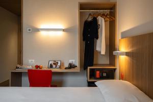 a hotel room with a bed and a red chair at Hotel Moov Porto Alegre in Porto Alegre