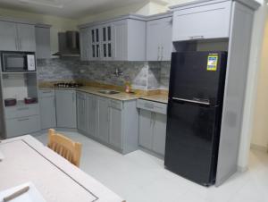 een keuken met een zwarte koelkast en grijze kasten bij Brand New 2 Bedroom Apartment Nemaa Bay in Sharm El Sheikh