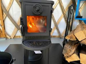 a wood stove with a fire in a room at Sweet Retreat and Yurt Farm in New Ipswich