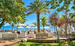 un complexe avec une plage bordée de chaises et de palmiers dans l'établissement DPNY Beach Hotel & SPA Ilhabela, à Ilhabela
