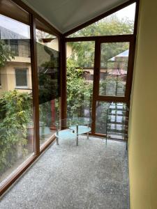 een kamer met grote ramen en een glazen tafel bij Airport Confort House in Otopeni