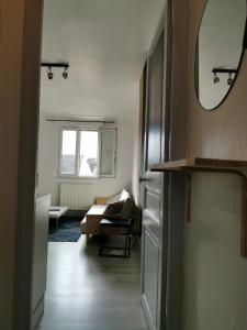 een woonkamer met een spiegel en een bank bij Appartement Cosy proche gare et centre ville in Reims