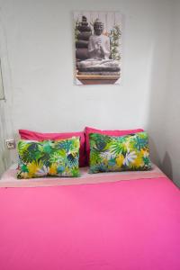 a pink bed with two pillows and a buddha at aparment puerto Alto in Madrid