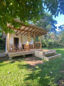 un patio con un banco y sillas bajo un árbol en Passion Fruit Lodge, en Cahuita