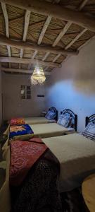 Habitación con 2 camas y lámpara de araña. en Maroc des Merveilles - Chez L'habitant, en Kalaat MGouna