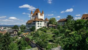 圖恩的住宿－Old town apt in the heart of Thun with garden，一座树冠茂密的山顶上的城堡