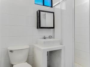 a white bathroom with a toilet and a sink at Casa Emma in Holbox Island